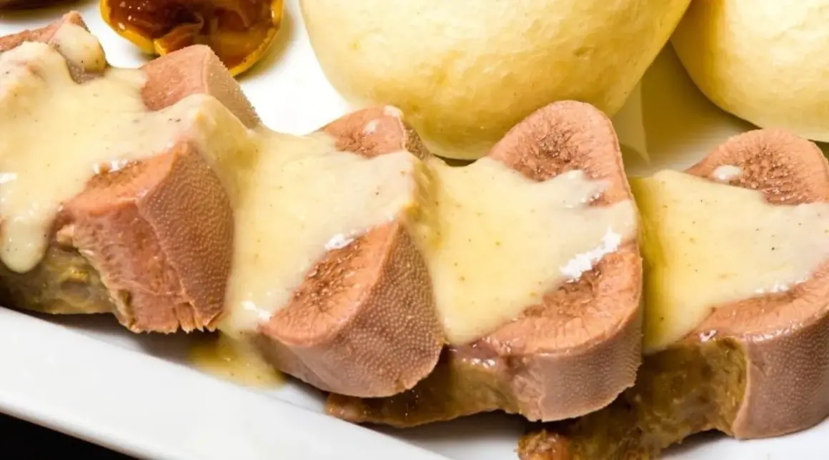 Pokrojone w plastry ozory wieprzowe w sosie, obok bułeczek. Jak wyciąć ślinianki w ozorach wieprzowych?