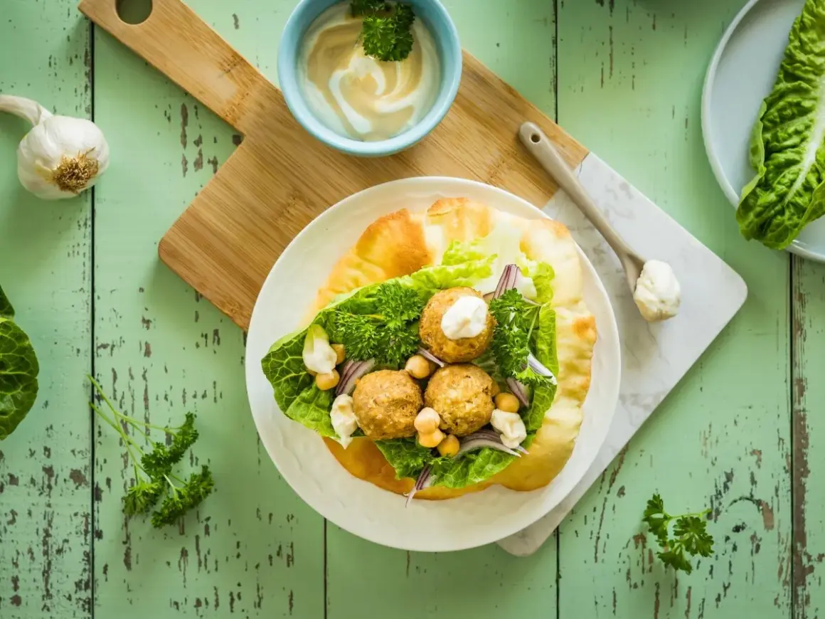 Jak przygotować sos tahini do sałatek i falafeli? Proporcje wody są kluczowe dla idealnej konsystencji. Falafel w picie z sałatą, ciecierzycą i sosem.