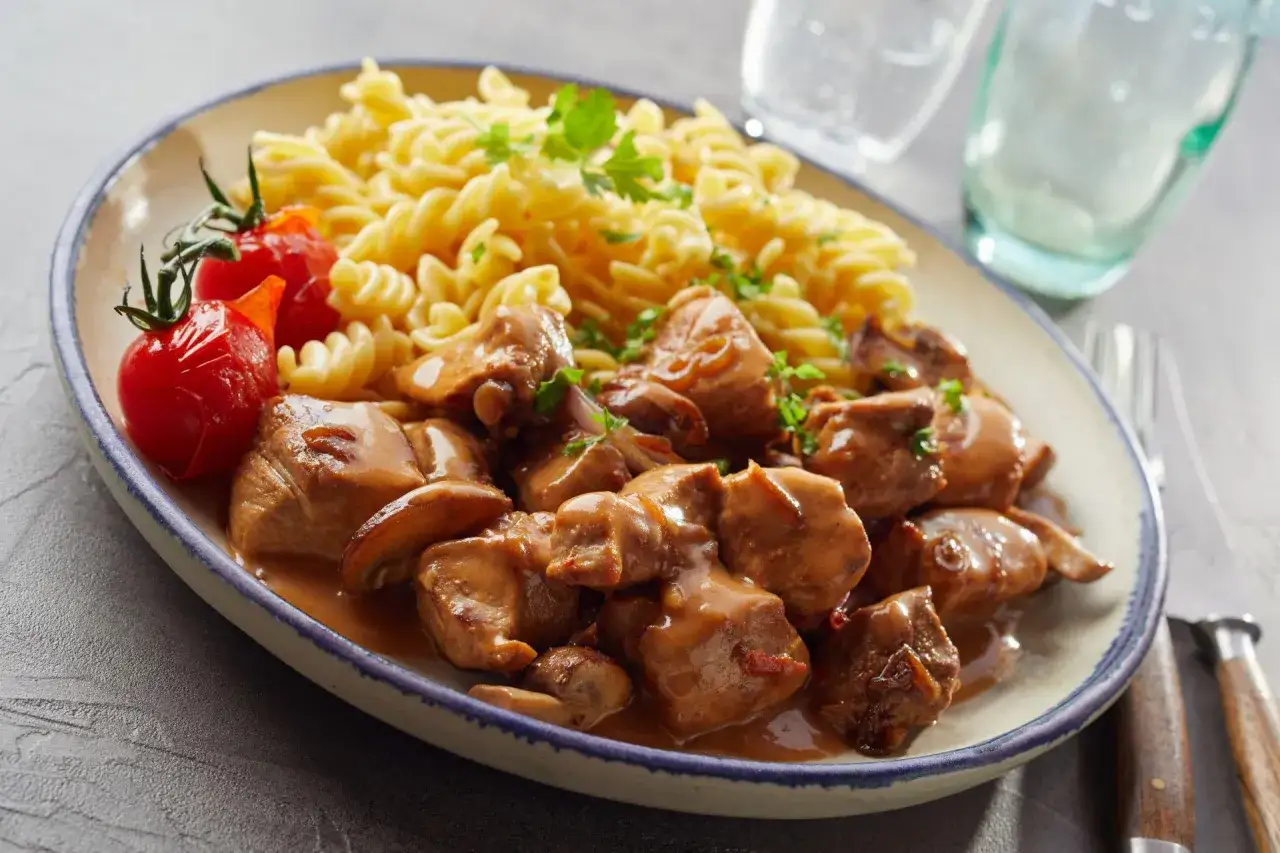 Pyszne danie z szynki wieprzowej w sosie z pieczarkami, podane z makaronem fusilli i pomidorkami. Oto co można zrobić z szynki wieprzowej!
