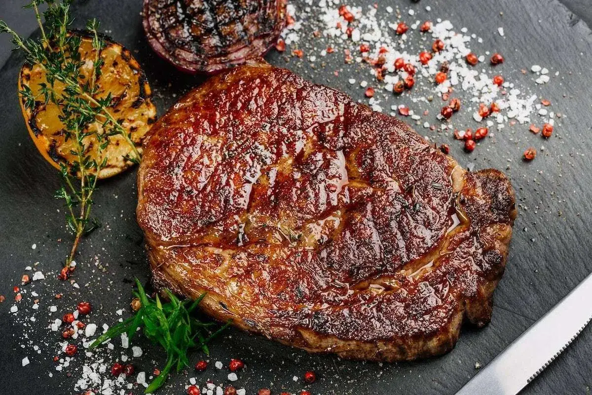 Soczysty rump steak, grillowana połówka cytryny i cebuli, posypane solą i pieprzem. Idealny na obiad.