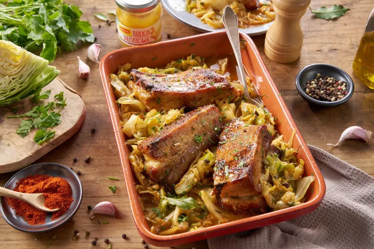 Pyszne, pieczone żeberka w kapuście, idealne na obiad. Obok składniki: kapusta, czosnek, papryka, przyprawy.