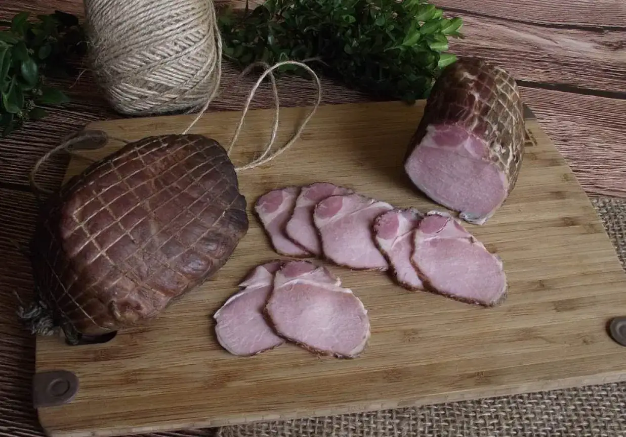 Wędzony schab w siatce, pokrojony w plastry. Zastanawiasz się, ile wędzić schab, by był idealny?