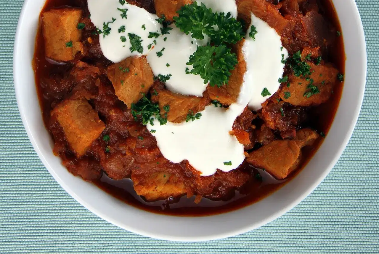 Gulasz wołowy z kleksem śmietany i natką pietruszki. Idealny sposób, jak zamarynować wołowinę do gulaszu, by była miękka i aromatyczna.