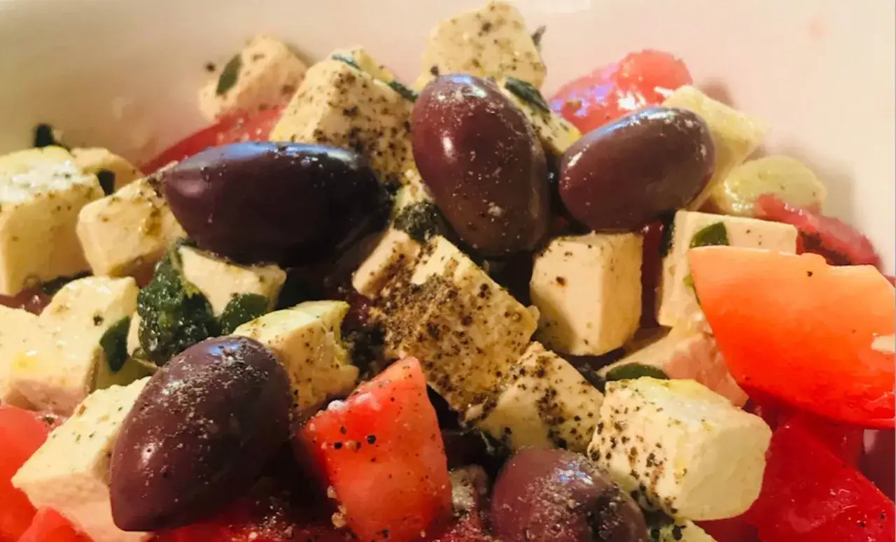 Sałatka z tofu, pomidorów i oliwek. Tofu pokrojone w kostkę, przyprawione, wygląda jak ser feta. Idealna na lato.