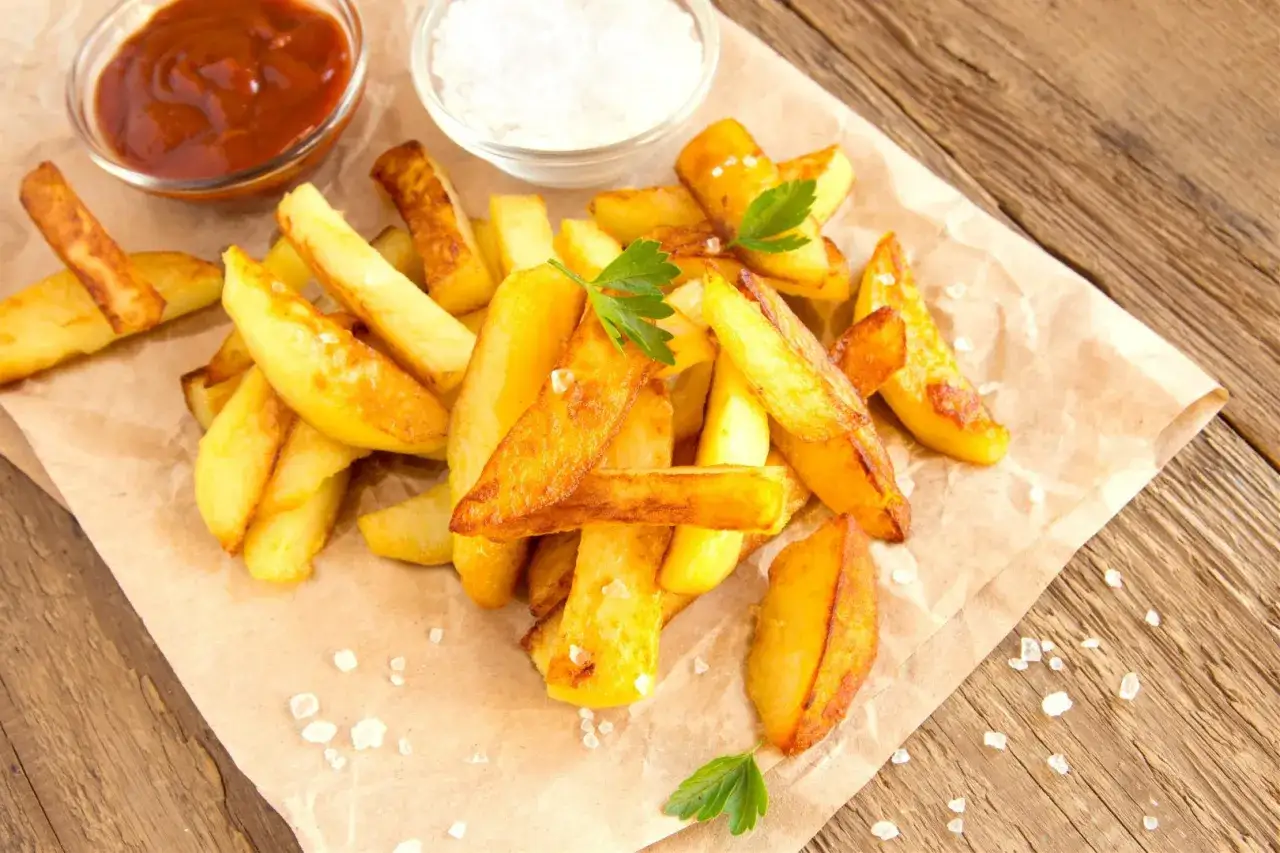 Jak dobrać grubość frytek do czasu smażenia: shoestring vs steak fries. Złociste frytki, ketchup i sól na papierze.