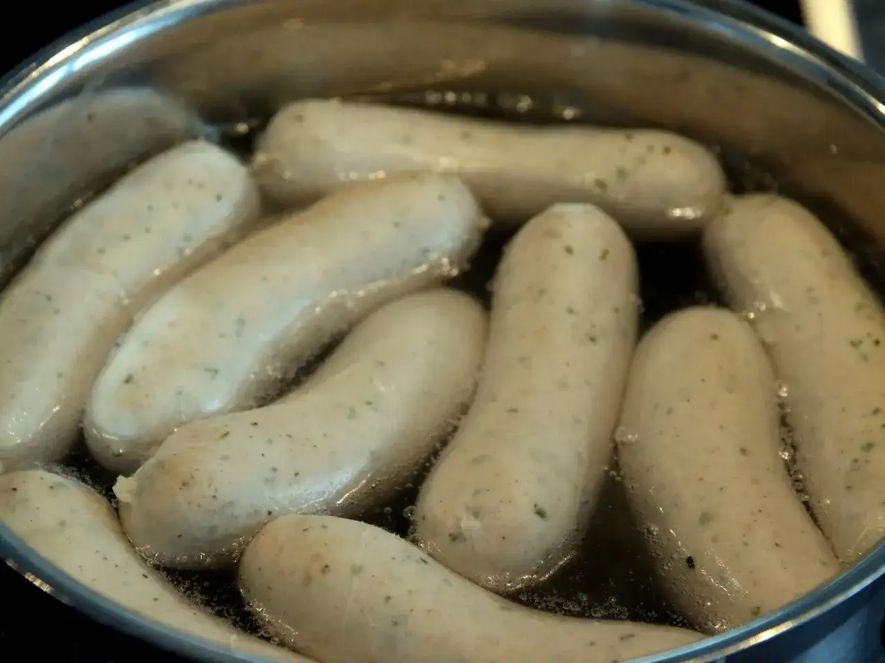 Biała kiełbasa gotuje się w garnku. Chcesz wiedzieć, jak szybko rozmrozić białą kiełbasę? Gotowanie to świetny sposób!