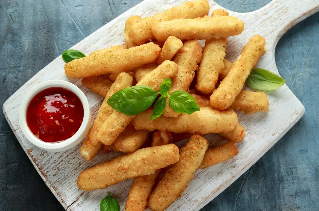 Chrupiące frytki z halloumi, idealna przekąska na imprezę, podane z sosem pomidorowym i listkami bazylii.