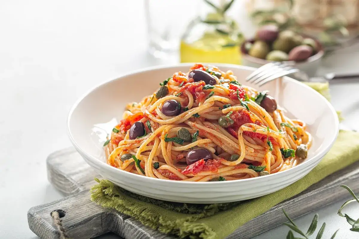 Pyszny makaron spaghetti z sosem pomidorowym, oliwkami i kaparami. Idealny przykład, jak zrobić sos do makaronu w stylu śródziemnomorskim.