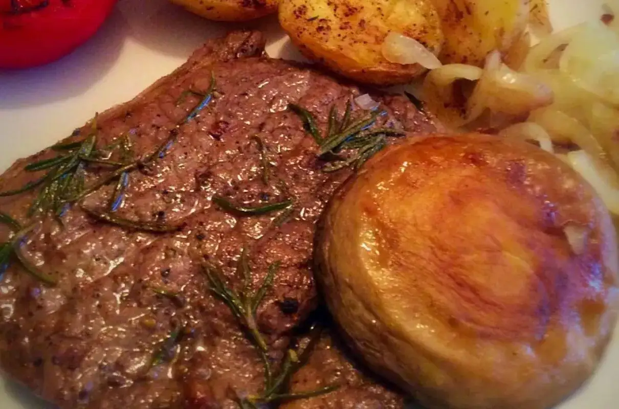 Soczysty rump steak z rozmarynem, pieczone ziemniaki i cebula. Pyszne danie, które pokazuje, co je rump steak.