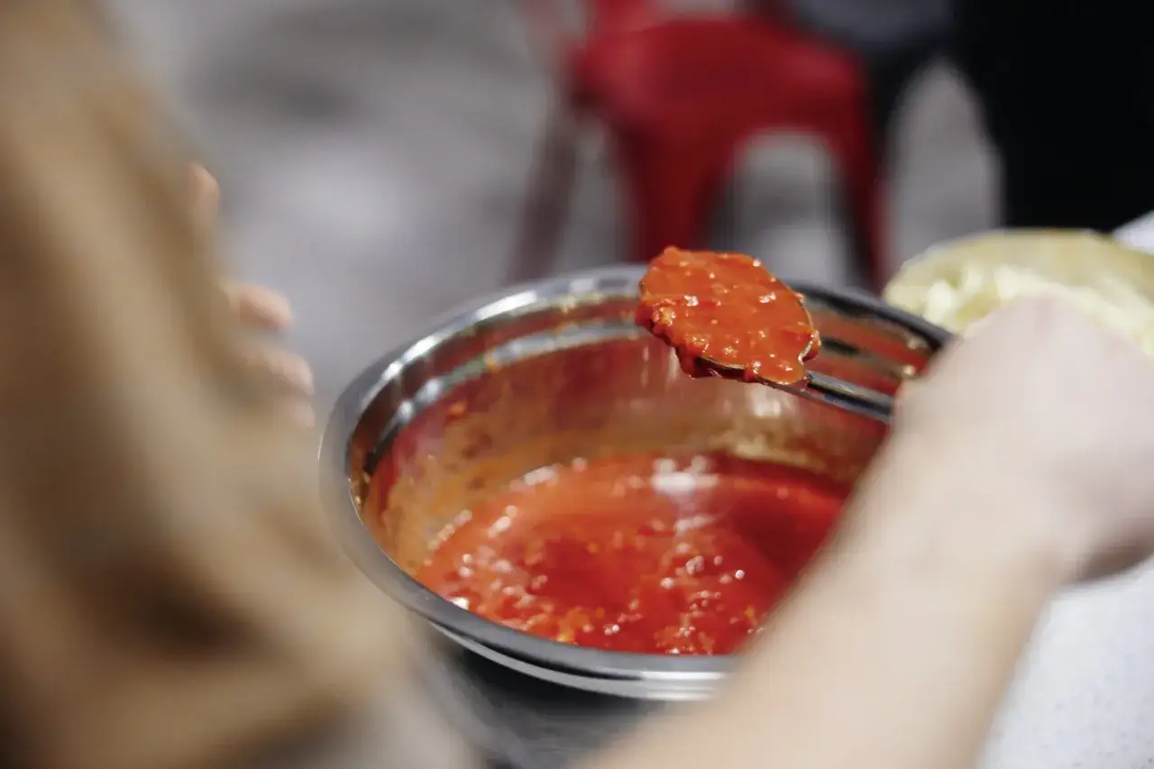 Łyżka z oryginalnym włoskim sosem do pizzy, gotowym do nałożenia na ciasto.
