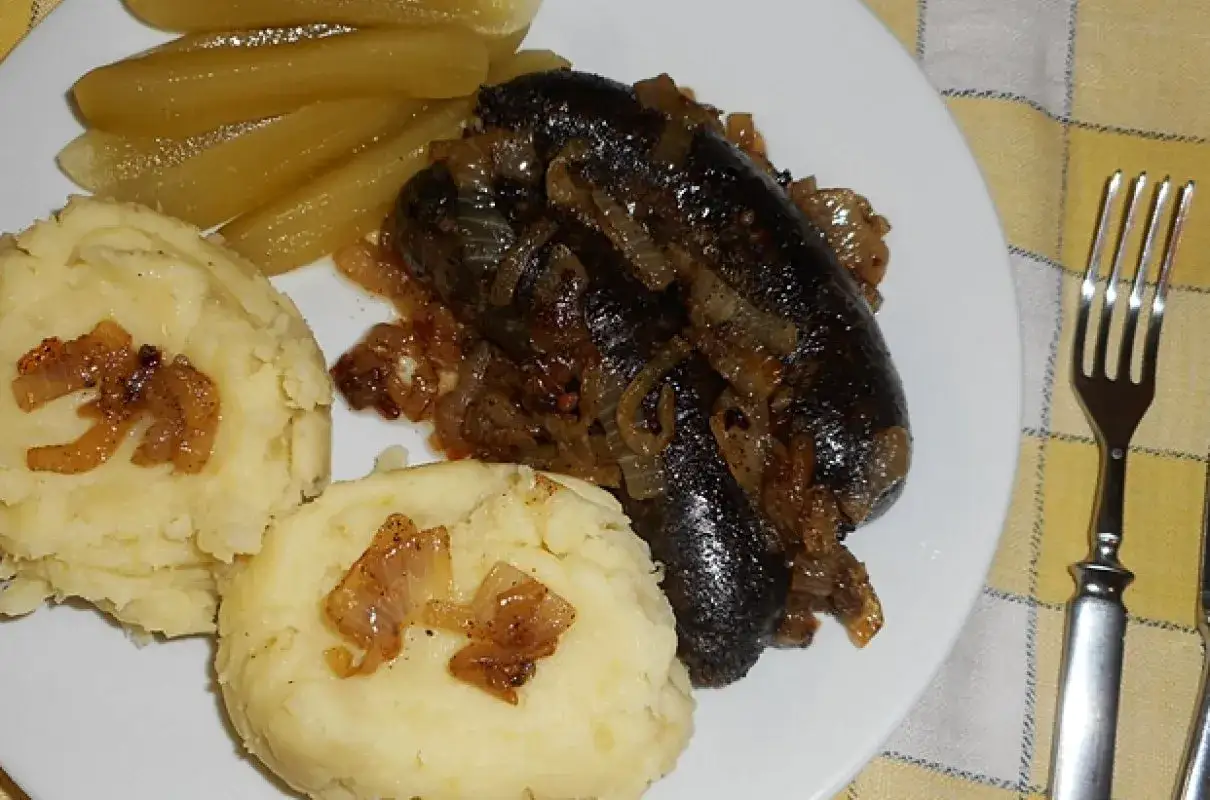 Kaszanka podsmażona z cebulką, podana z puree ziemniaczanym i ogórkami kiszonymi. Idealny sposób, jak podsmażyć kaszankę.