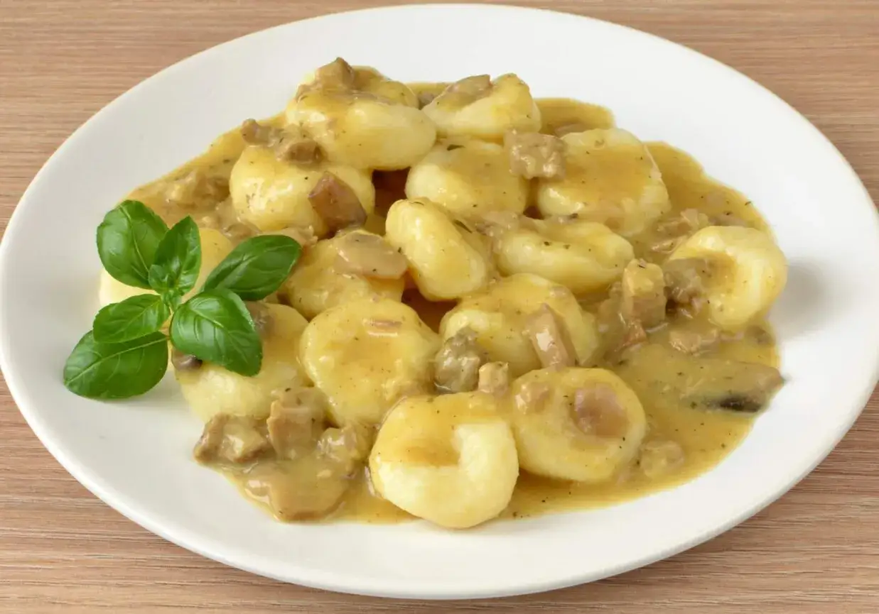 Pyszne kluski śląskie w sosie grzybowym z kawałkami grzybów i mięsa. Idealne danie, które świetnie smakuje i pokazuje, co pasuje do sosu grzybowego.