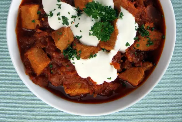 Gulasz wołowy z kleksem śmietany i natką pietruszki. Idealny przepis, jak zamarynować wołowinę do gulaszu, by była miękka i aromatyczna.