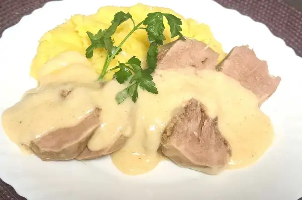Jak zrobić ozorki w sosie chrzanowym: delikatne ozorki w kremowym sosie z chrzanem, podane z purée ziemniaczanym i natką pietruszki.