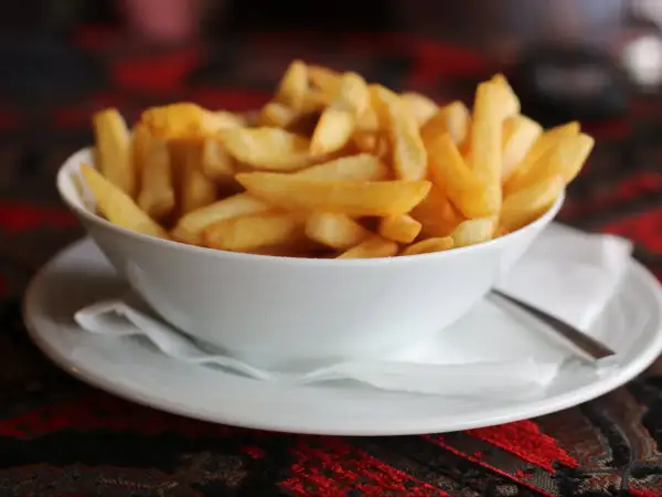 Chrupiące frytki domowe jak z restauracji krok po kroku. Złociste, idealne ziemniaczki w białej miseczce.