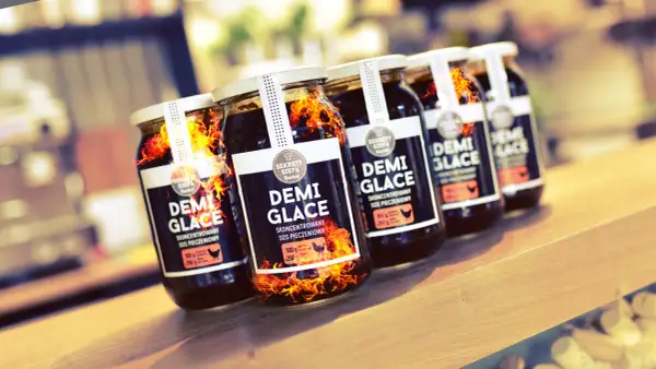 Słoiki z sosem demi-glace, jak zrobić idealny sos demi-glace bez 48 godzin gotowania. Płomienie sugerują intensywny smak.