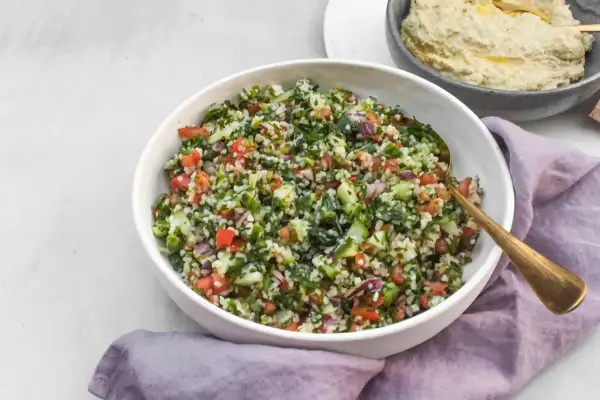 Kolorowa sałatka tabbouleh z komosą ryżową, pomidorami, ogórkiem i ziołami. Idealna alternatywa dla tradycyjnej wersji.