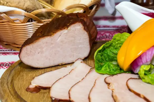 Gotowy do wędzenia schab, pokrojony w plastry, z dodatkiem warzyw i koszyka z pieczywem. Idealny przepis na to, jak przygotować schab do wędzenia.