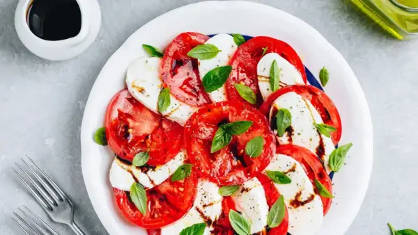 Sałatka caprese z pomidorami i mozzarellą. Woda w sałatce może pojawić się z powodu dojrzałości pomidorów lub nadmiaru sosu.