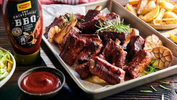 Soczyste żeberka BBQ z czosnkiem i rozmarynem, idealnie pasują do żeberek, a obok sos i frytki.